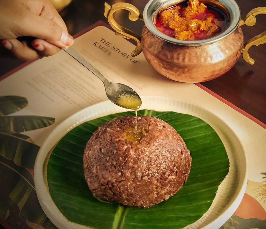Ragi mudde on a banana leaf, with ghee poured over it and natu kodi kura in a copper pot